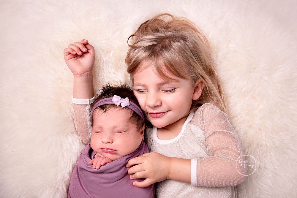 a photo of a newborn baby girl and her sister at her newborn photo session