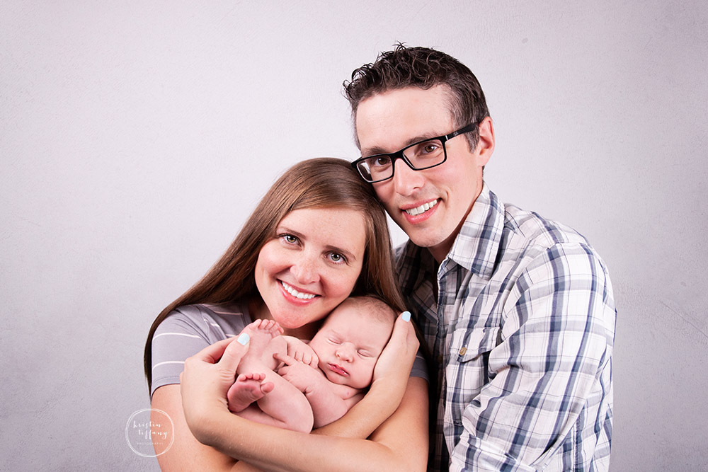 a photo of a newborn baby boy and his parents at a newborn photoshoot