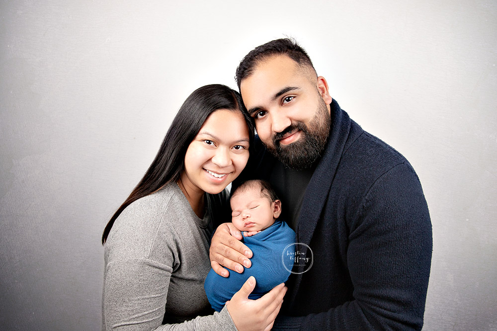 a photo of a baby boy and his parents at a newborn photo shoot