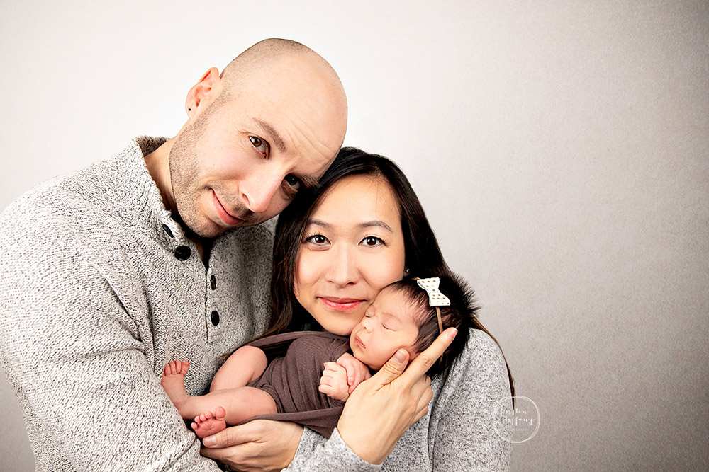 a photo of a baby girl and her parents at her newborn photo session