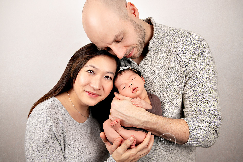 a photo of a baby girl and her parents at her newborn photo session
